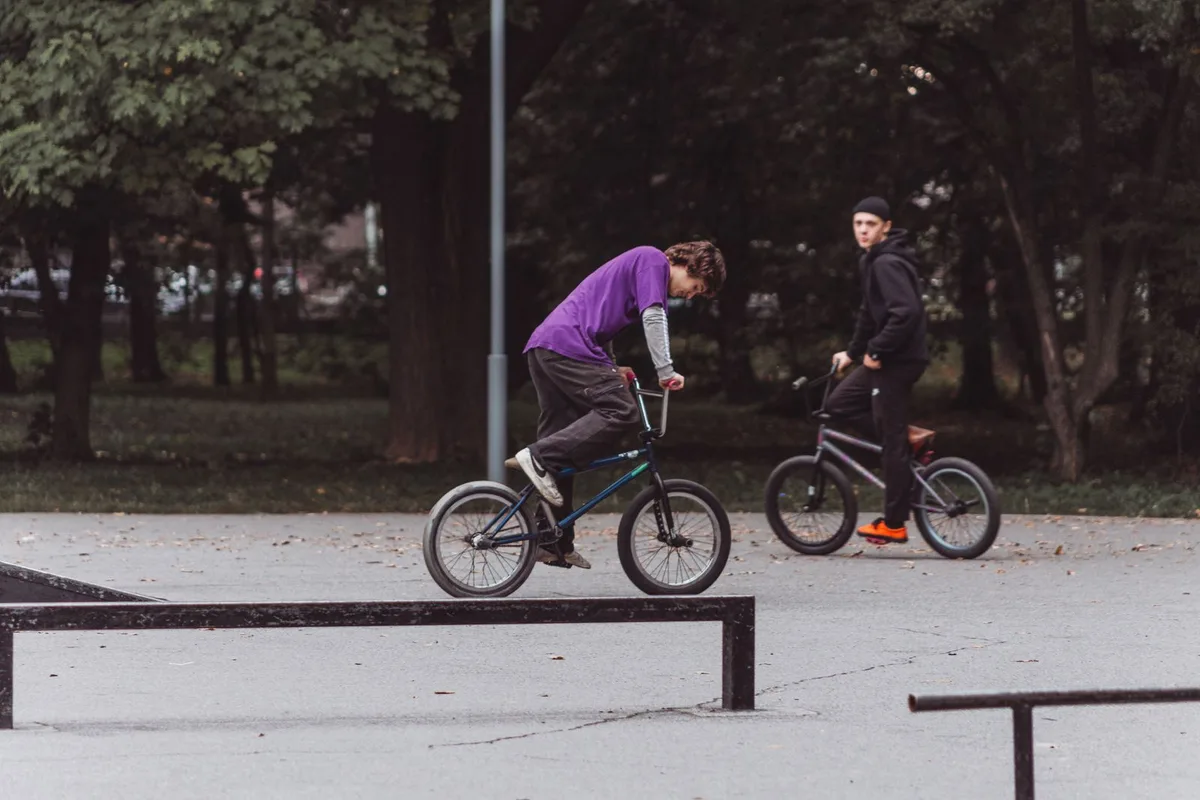 Двое подростков катаются на BMX-велосипедах в осеннем парке