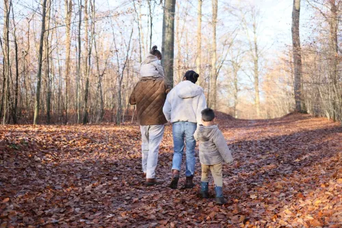 Родители с детьми идут по осеннему лесу по тропинке, усыпанной рыжими листьями