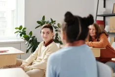 Подростки в светлом классе разговаривают с преподавателем